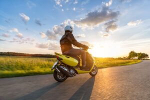 Person riding their motorcycle towards the sun with a beautiful landscape in the background